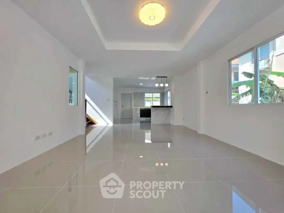 Spacious modern living room with glossy tiled floors and open kitchen layout.