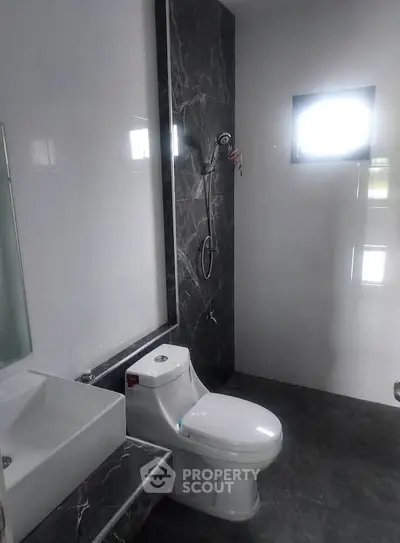 Modern bathroom with sleek design and elegant fixtures, featuring a stylish toilet and shower area.