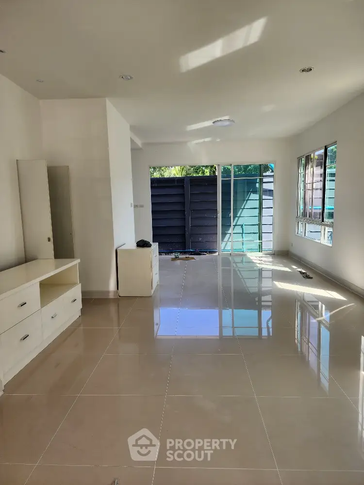 Spacious living room with glossy tiled floors and large windows for natural light