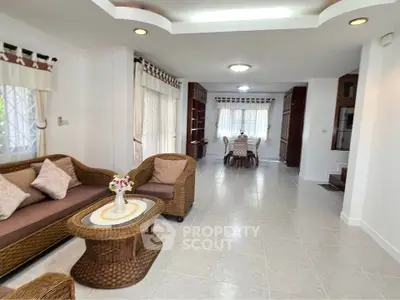 Spacious living room with elegant wicker furniture and dining area in modern home.