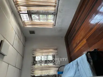Cozy bedroom with wooden floors and natural light from large windows.
