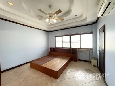 Spacious bedroom with large windows, ceiling fan, and built-in wooden platform bed, offering a blank canvas for personalized decor.