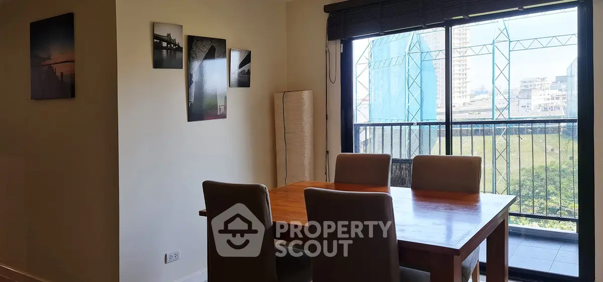 Bright dining area with wooden table and chairs, featuring a balcony view in a modern apartment.