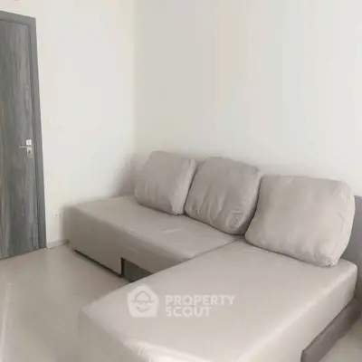 Modern minimalist living room with sleek gray sofa and wooden door, perfect for cozy relaxation.