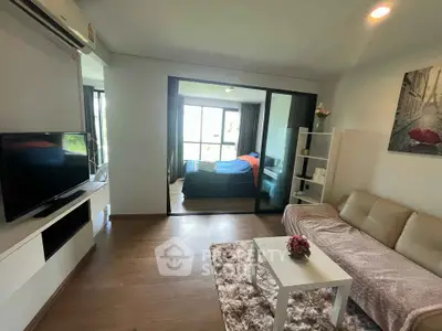 Modern living room with cozy sofa and TV, leading to a bright bedroom with large windows.
