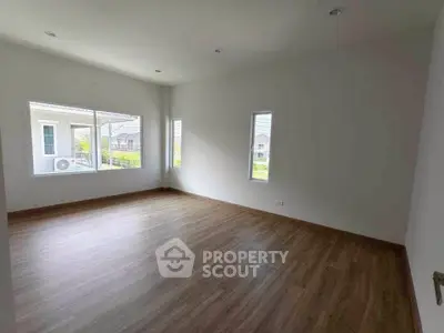 Spacious empty room with large windows and wood flooring in modern home