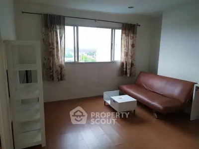 Spacious living room with modern sofa and natural light from large window.