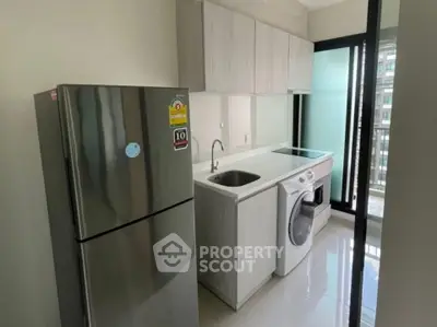 Modern kitchen with sleek appliances and washing machine in compact layout.