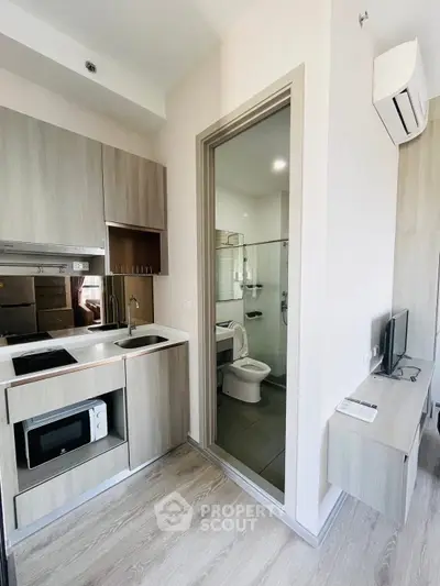 Modern compact kitchen with integrated bathroom in sleek apartment design.