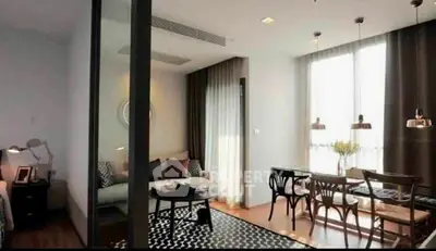 Modern living room with dining area, featuring stylish furniture and large windows for natural light.