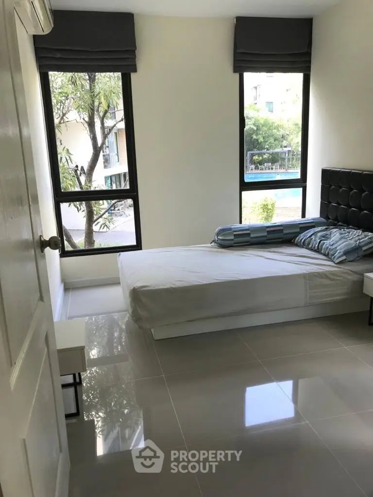 Bright bedroom with large windows and modern furnishings in a stylish apartment.