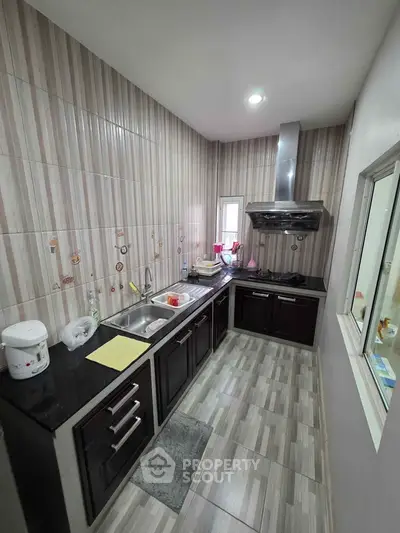 Modern kitchen with sleek cabinetry and tiled walls, featuring a gas stove and ample counter space.