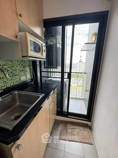 Compact kitchen with modern appliances and balcony view in urban apartment