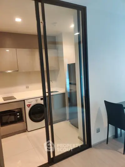 Modern kitchen with sliding glass door, featuring built-in oven and washing machine.