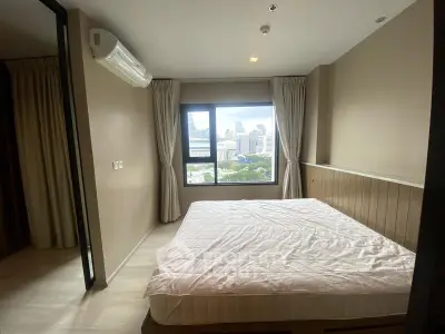 Spacious bedroom with city view in modern apartment, featuring large window and neutral decor.