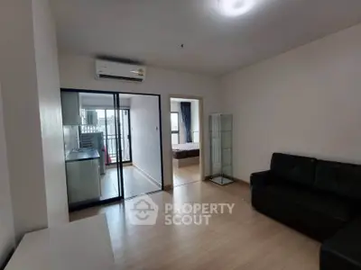Modern apartment interior with open living room and view into bedroom, featuring sleek furniture and natural light.