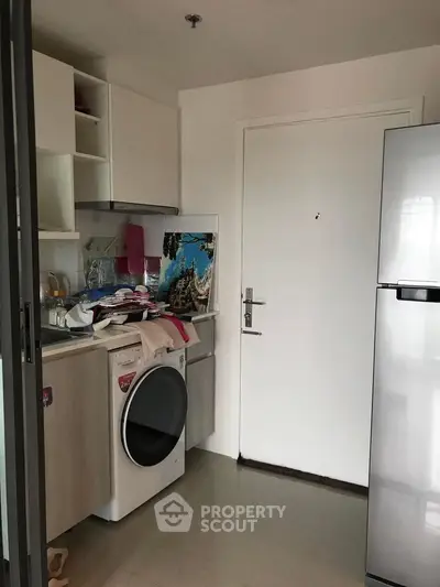 Compact kitchen with washing machine and fridge in modern apartment