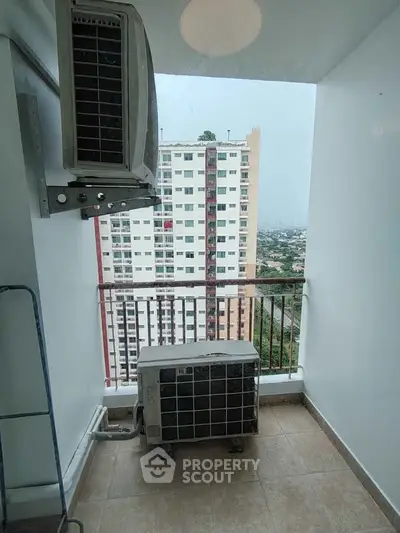 Compact balcony with air conditioning unit and city view in modern apartment building.