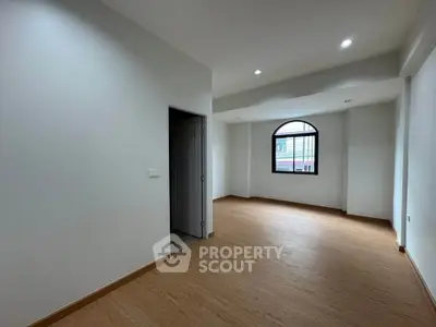 Spacious empty room with wooden flooring and large window, perfect for customization.