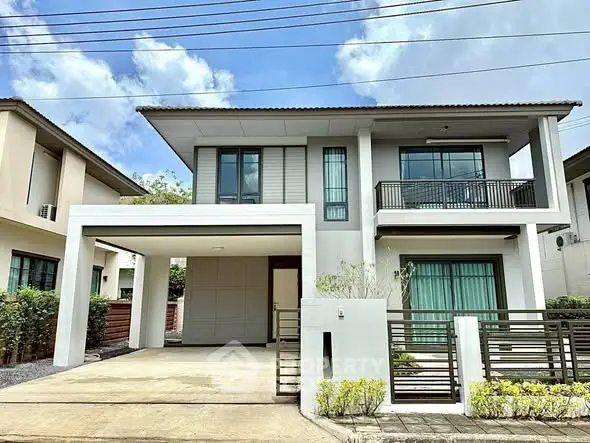 Modern two-story house with balcony and spacious driveway in a serene neighborhood.