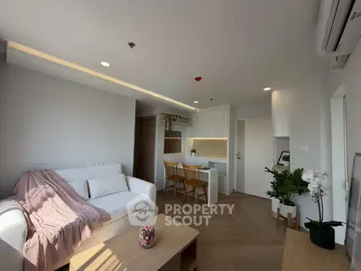 Modern living room with cozy sofa, stylish decor, and open kitchen layout in a bright apartment.