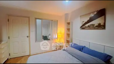 Cozy bedroom with modern decor and cityscape artwork, featuring a comfortable bed and soft lighting.