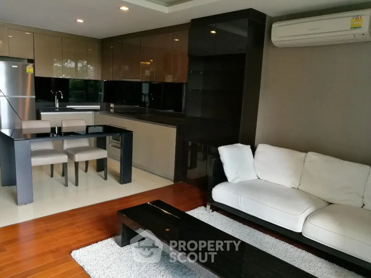 Modern open-layout living room with sleek kitchen, cozy sofa, and stylish dining area.