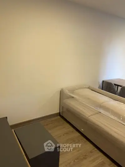 Modern bedroom with minimalist design and wooden flooring, featuring a bed and a small table.