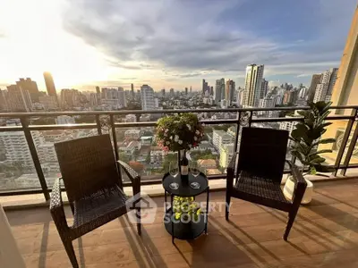 Stunning cityscape view from a high-rise balcony with cozy seating and lush plants.