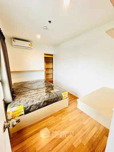 Cozy bedroom with wooden flooring and air conditioning in modern apartment