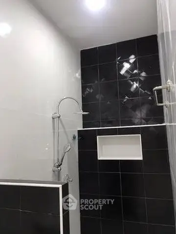 Modern bathroom with sleek black and white tiles and a stylish shower setup.