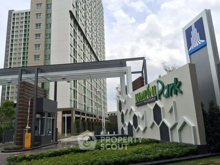 Modern condominium entrance with stylish signage and high-rise building in the background.