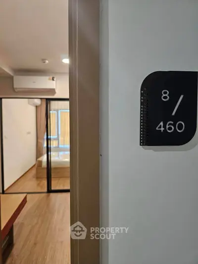 Modern apartment entrance with room number and glimpse of stylish interior design.