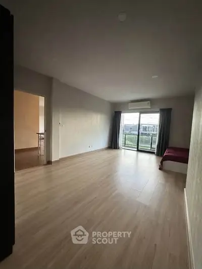 Spacious living room with wooden flooring and large window offering natural light and scenic view.