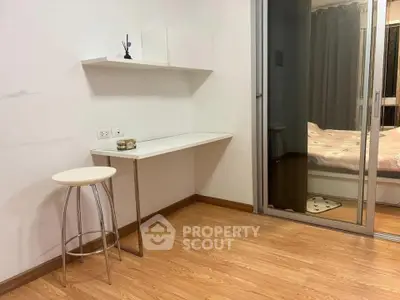 Modern apartment with cozy bedroom and study area featuring sleek wooden flooring.