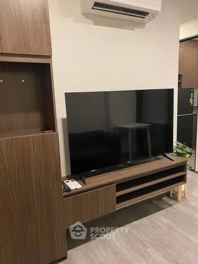 Modern living room with sleek wooden furniture and large flat-screen TV, perfect for entertainment.