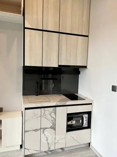 Modern compact kitchen with sleek cabinetry and marble countertops