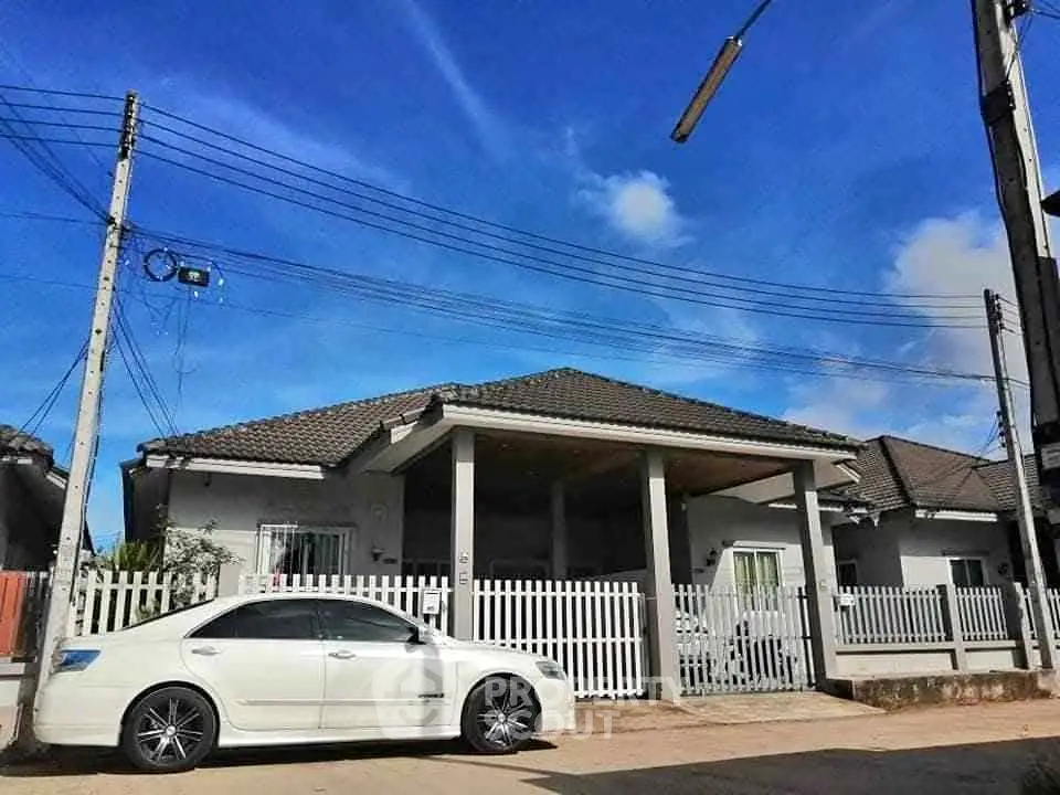 Charming single-story house with a white picket fence and driveway, perfect for family living.