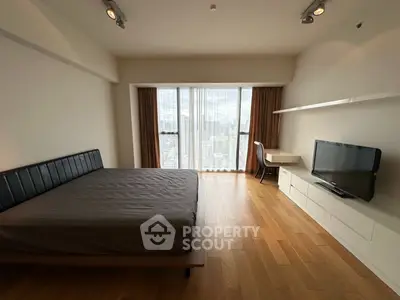 Spacious bedroom with city view, modern furnishings, and natural light.