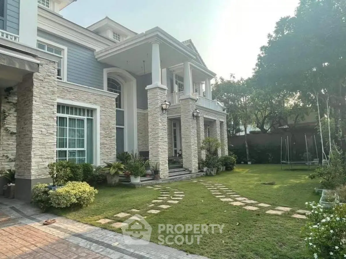 Elegant two-story house with stone facade and lush garden