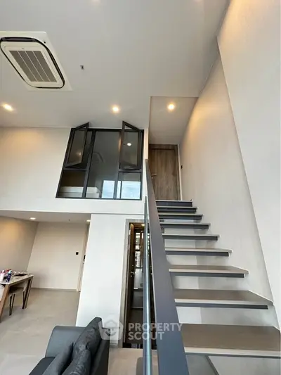Modern loft apartment with sleek staircase and high ceilings, featuring an open mezzanine and stylish interior design.