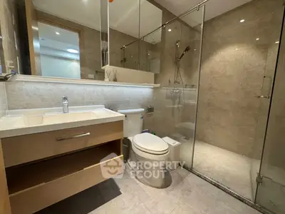 Modern bathroom with glass shower and sleek vanity in upscale apartment.