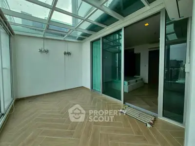 Spacious balcony with glass ceiling and sliding doors, perfect for relaxation.