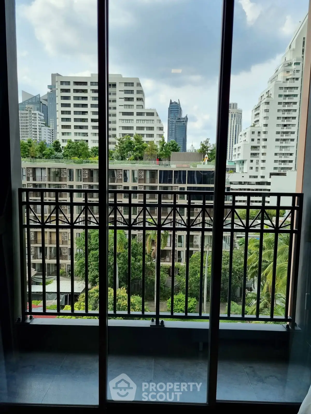 Stunning cityscape view from a modern apartment balcony with lush greenery.