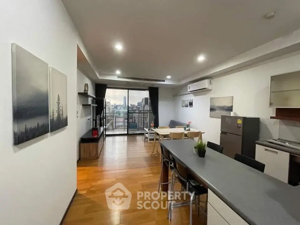 Spacious modern living room with open kitchen and city view balcony, perfect for urban living.