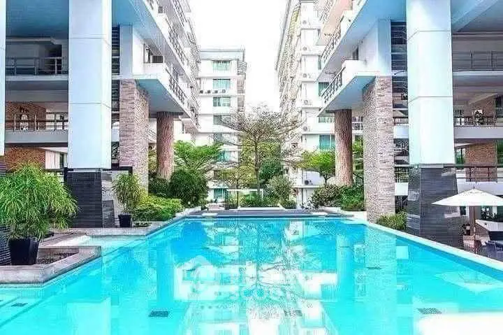 Luxurious modern apartment complex with stunning pool and lush greenery.