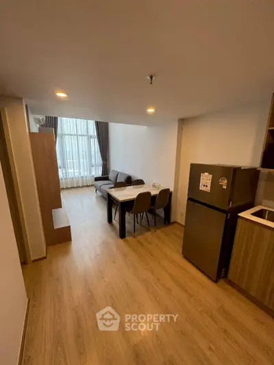 Modern living room with dining area and kitchenette in open layout apartment.