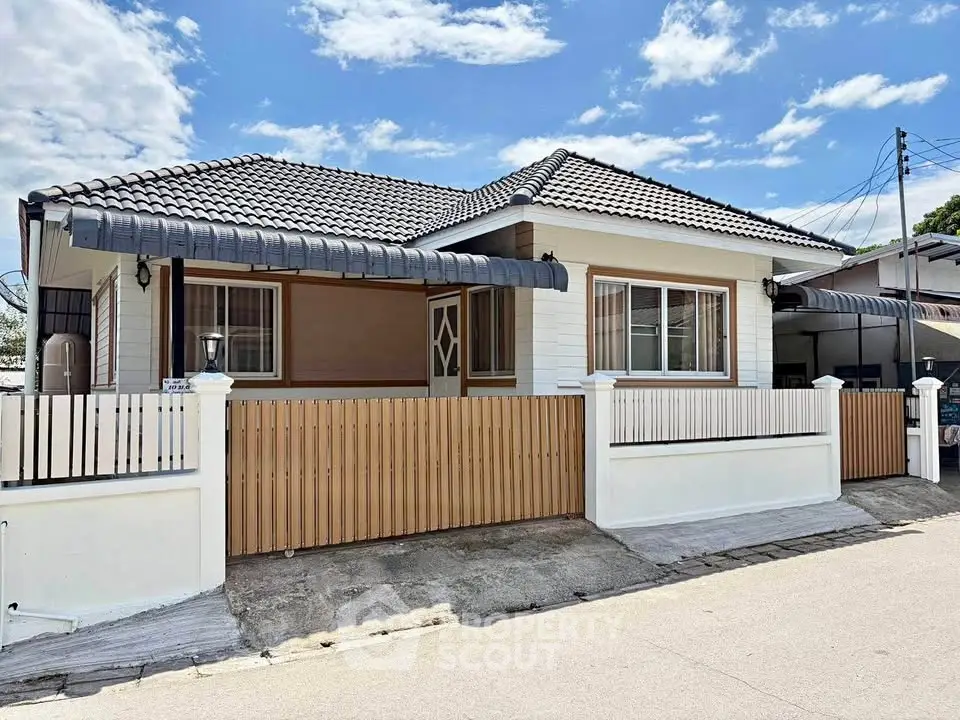 Charming single-story house with tiled roof and fenced yard in a serene neighborhood.