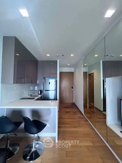 Modern kitchen with sleek cabinetry and mirrored wall in stylish apartment
