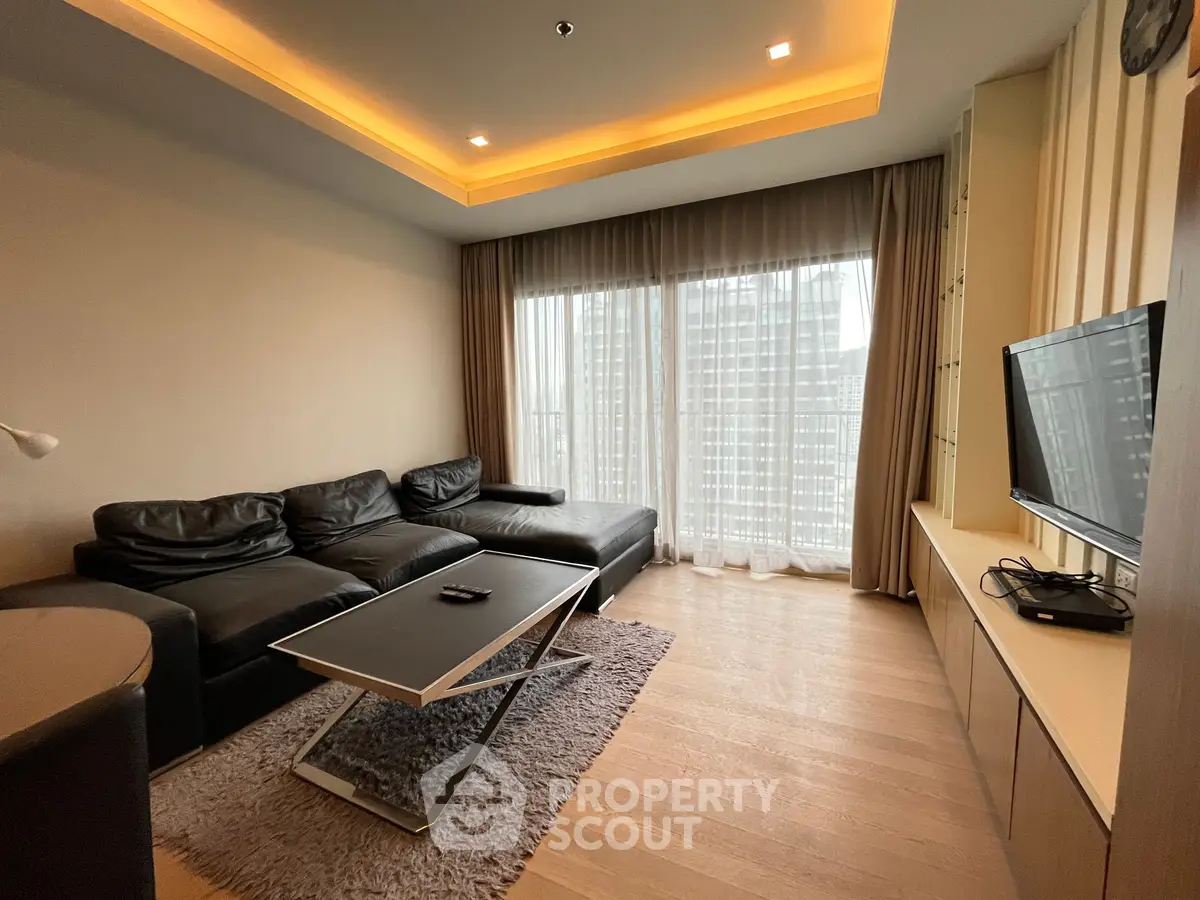 Modern living room with sleek black leather sofa and large window view